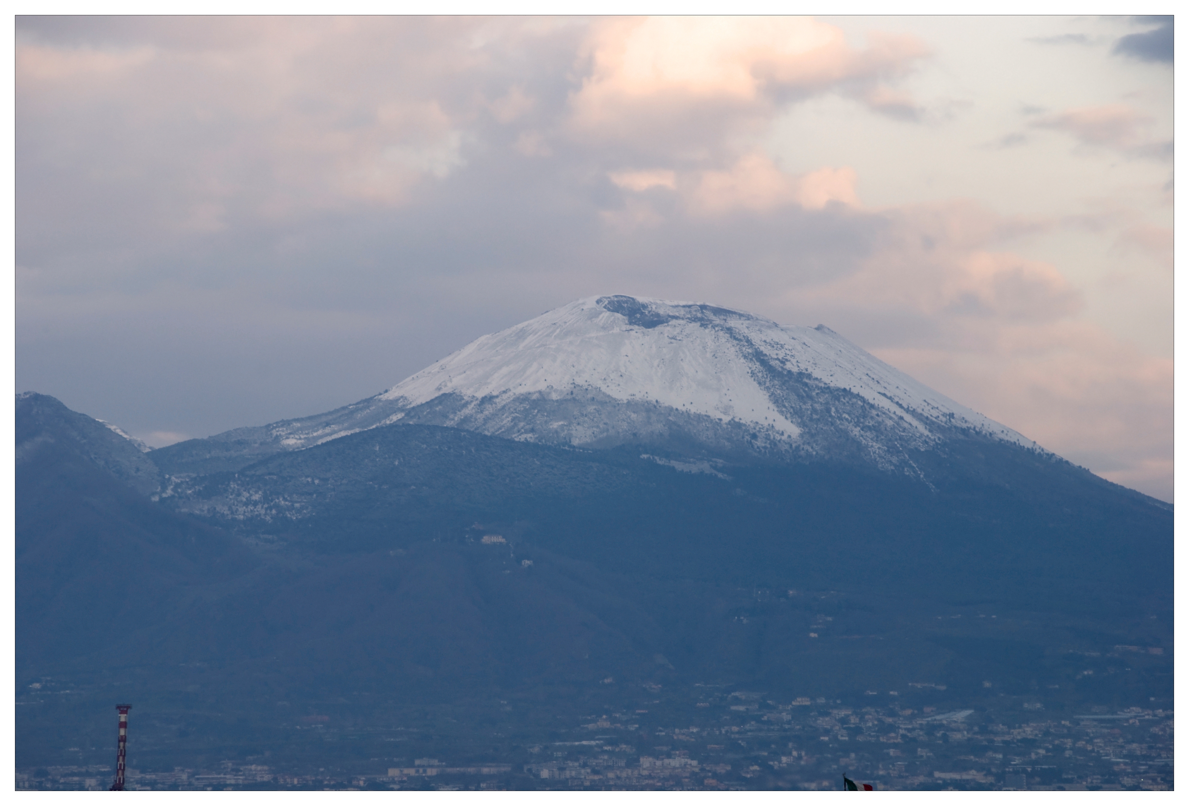 Panorama di Napoli al tramonto con il Vesuvio innevato e il porto